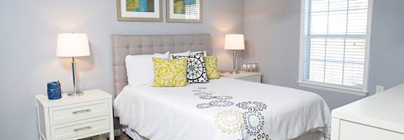A bedroom with a bed, nightstand, and two lamps.