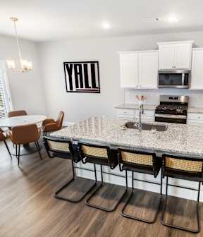 A kitchen with a granite countertop and white cabinets. at Herrin Farms, Auburn, 30011