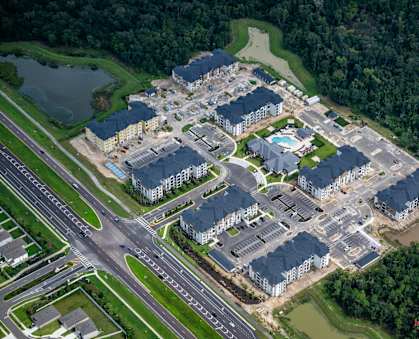 An aerial view of a large housing complex with a swimming pool and a road running through it.