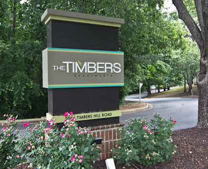 a sign for the timbers apartments on the side of a road