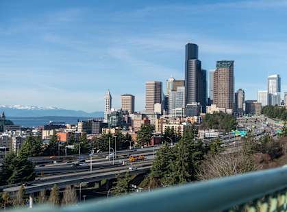 A cityscape with a highway in the foreground and mountains in the background.