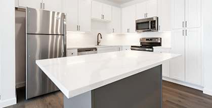 A kitchen with a white countertop and stainless steel appliances.