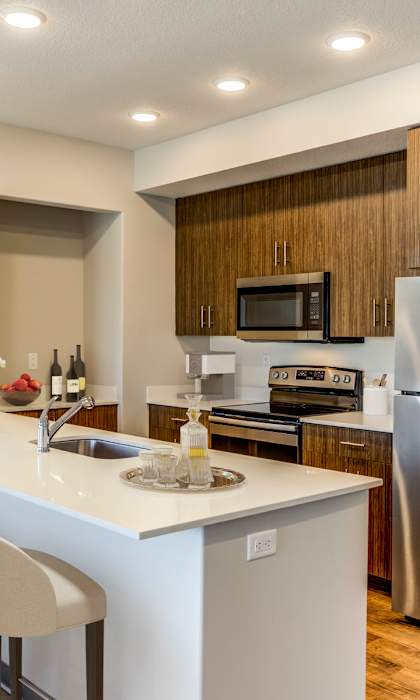A kitchen with a refrigerator, microwave, oven, and sink.