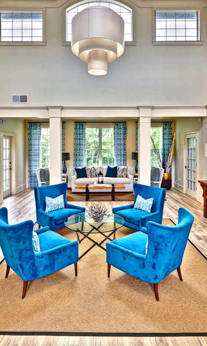 A living room with blue chairs and a fireplace.