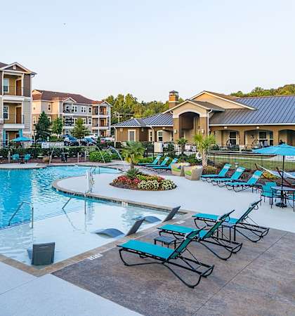 an empty swimming pool with lounge chairs and apartments in the background