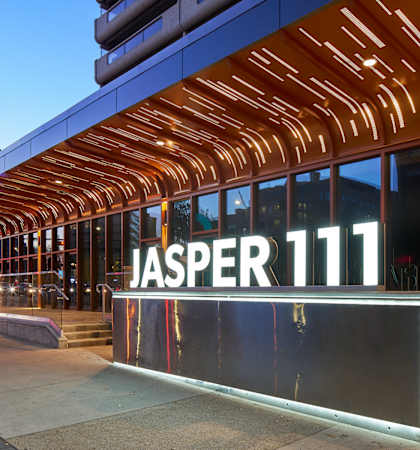 A modern building with a glass facade and a wooden structure above the entrance.