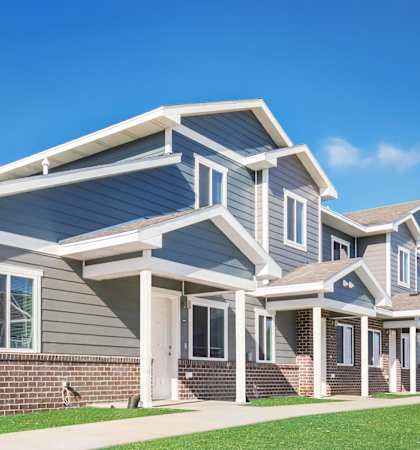 A modern house with a grey and white exterior and a brick base.