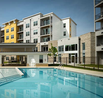 a swimming pool with an apartment building in the background at Woodmore Grand Apartments in Bowie, MD