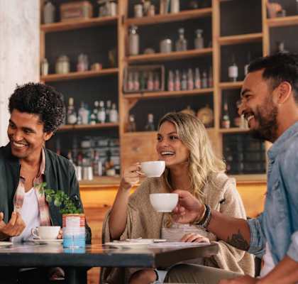 Four people are having a conversation over coffee in a cozy café setting.