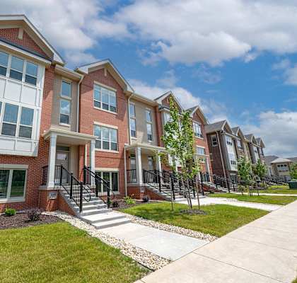 a row of brick apartment buildings with stairs and grass