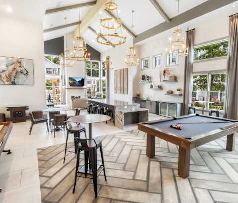 A pool table is in the middle of a room with a dining table and chairs.