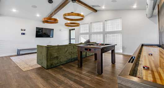 A room with a pool table and a green couch.