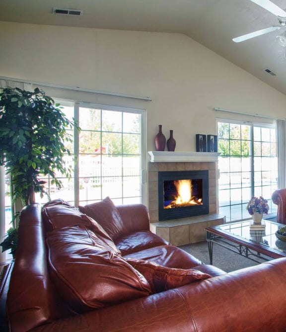 a living room with leather furniture and a fireplace  at Country Oaks Apartments in Clearfield, Utah
