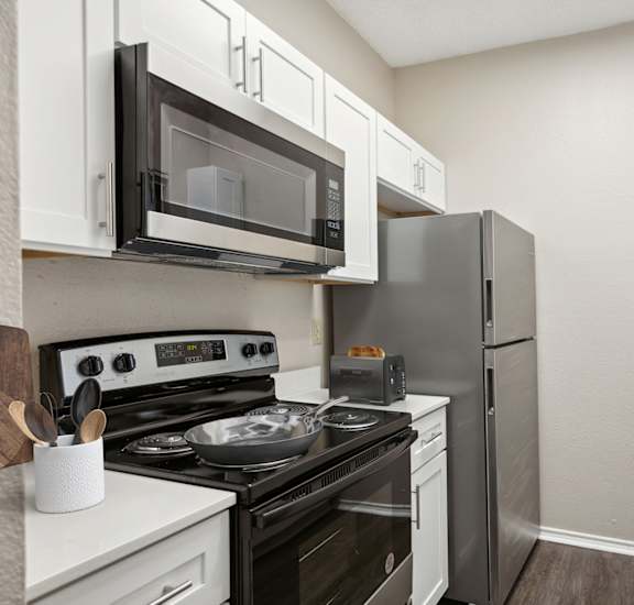 an apartment kitchen with stainless steel appliances and white cabinets at Canyon Creek, Texas, 78759