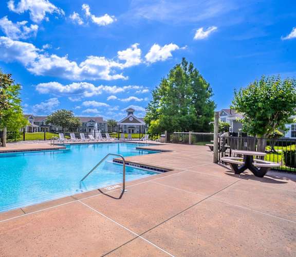 A large outdoor swimming pool surrounded by a fence and trees.