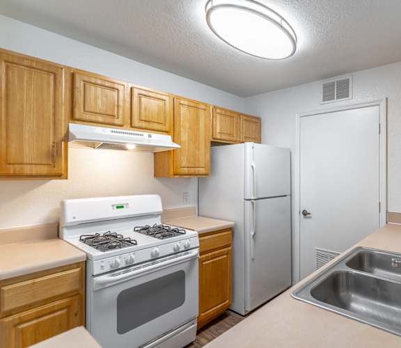 A kitchen with a stove, refrigerator, and sink.