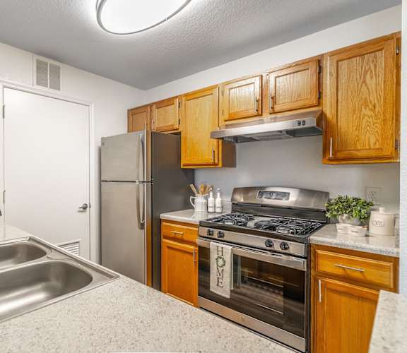 A kitchen with wooden cabinets and a stainless steel oven.