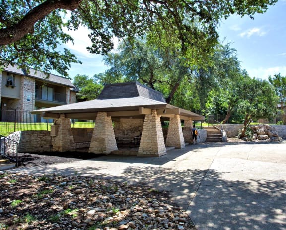 a stone gazebo with a basketball hoop in a courtyard