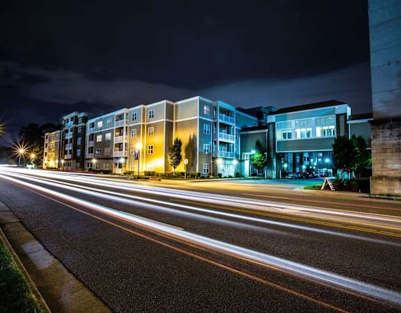 A long exposure shot of a street at night with light trails from moving vehicles.