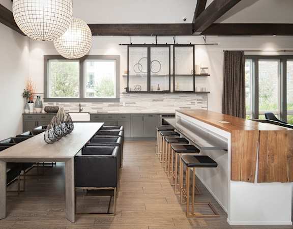 a dining room with a long wooden table and chairs and a kitchen with a bar