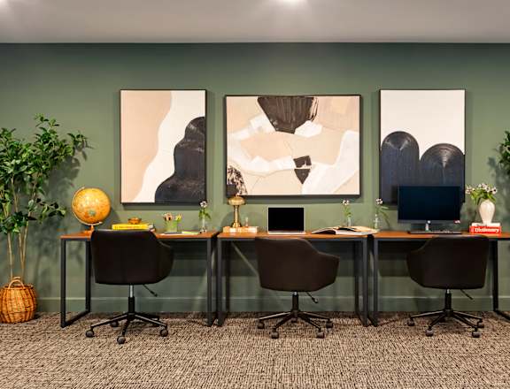 A room with a green wall and a desk with a computer and a lamp.