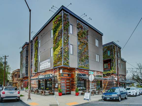 a building with plants growing on it on the side of a street