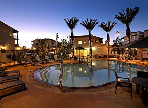 A pool surrounded by palm trees and lounge chairs.