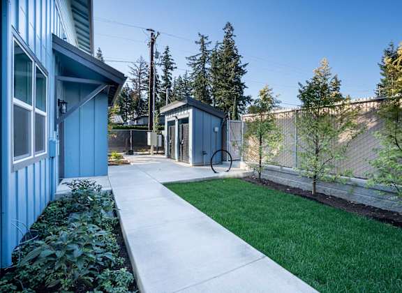 A blue house with a white walkway leading to a small building.