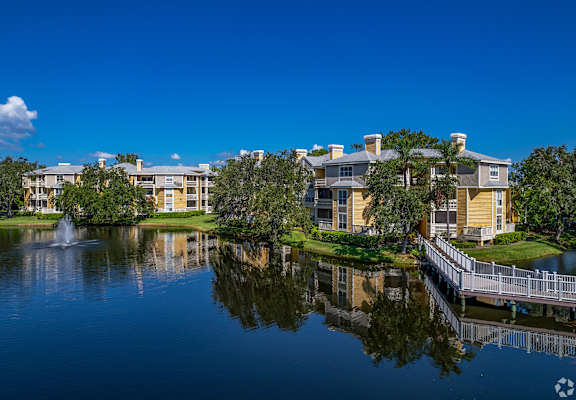 A serene lake reflects the buildings and sky in the image.