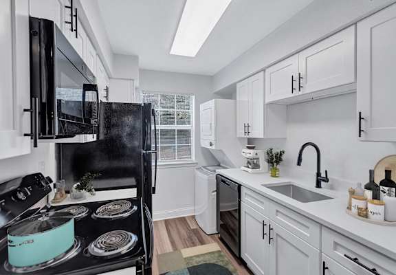 A modern kitchen with a black stove top and white cabinets.