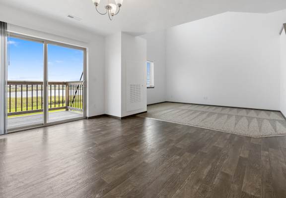 A room with a wooden floor and a sliding glass door leading to a balcony.