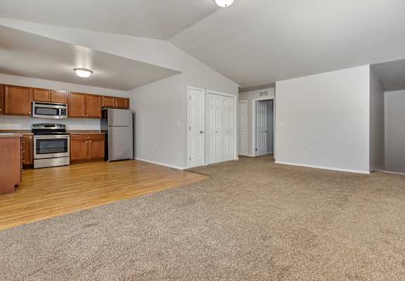 A spacious living room with a kitchen area in the background.