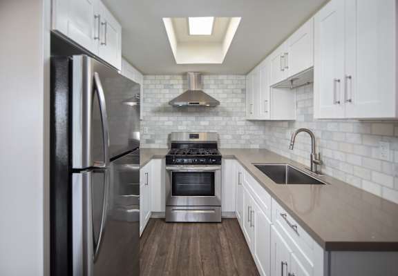 A modern kitchen with a stainless steel refrigerator and a stove top oven.
