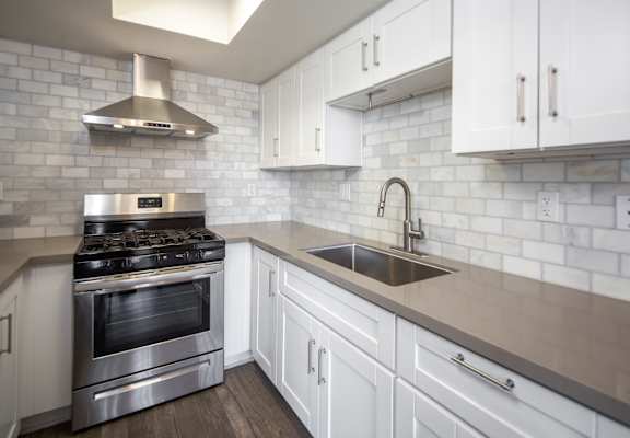 A modern kitchen with a stainless steel oven and white cabinets.