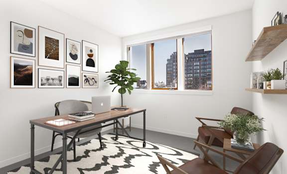 Home office with a desk and a window and a wall of framed photos