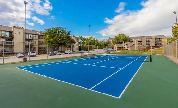 a tennis court with apartments in the background