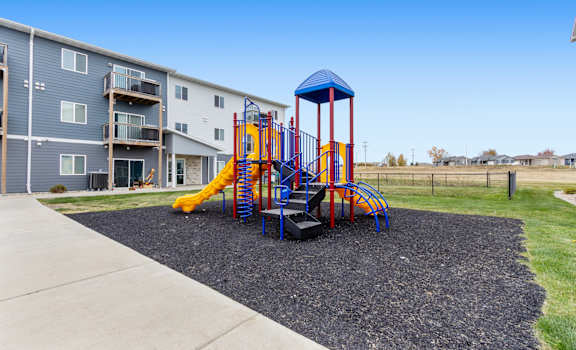 A playground with a blue and yellow slide and a red and blue tower.