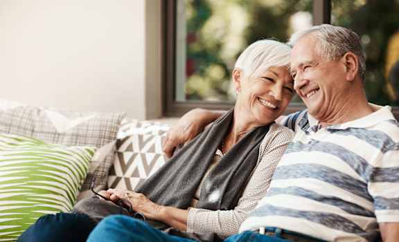 an older couple sitting on a couch with their arms around each other