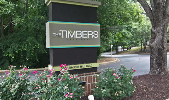 a sign for the timbers apartments on the side of a road