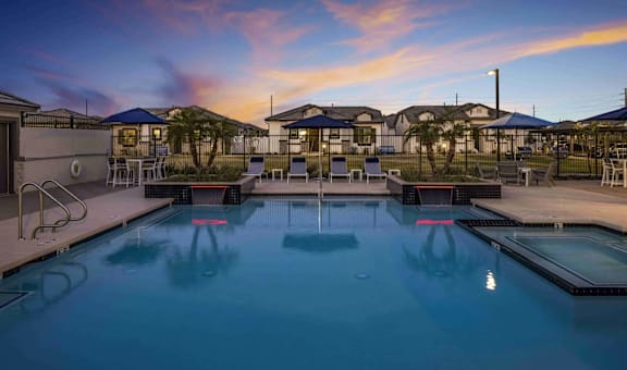 A swimming pool at a resort with a sunset in the background.