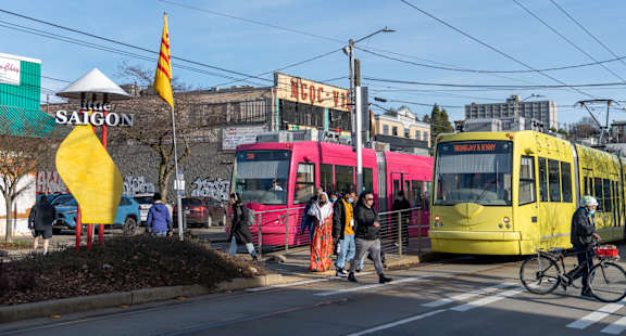 A yellow tram is parked on the side of the street.