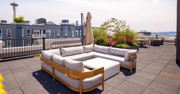 A patio with a white couch and a wooden table.