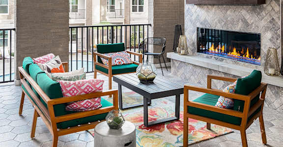 a living room with a fireplace and a balcony with chairs and a table