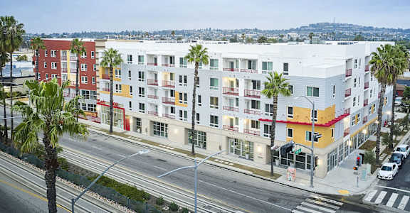 a large apartment building with palm trees in front of it