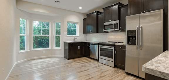 an empty kitchen with stainless steel appliances and black cabinets