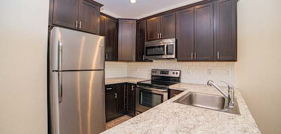 a kitchen with dark wood cabinets and white granite countertops