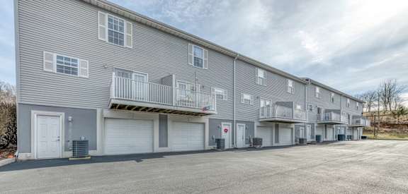 A grey apartment building with a parking lot in front.