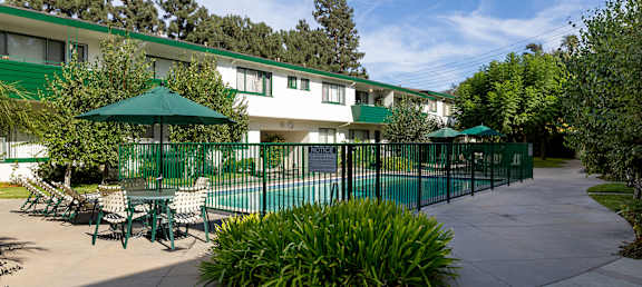 A green umbrella is in front of a white building.