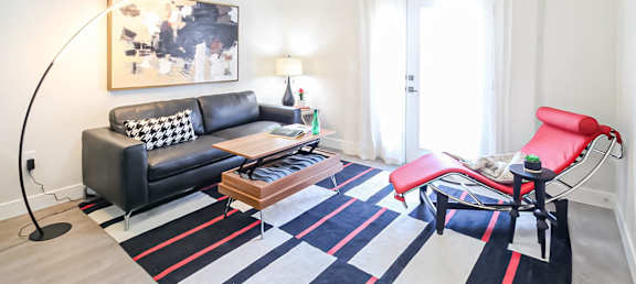 a living room with a blue and white rug and leather furniture