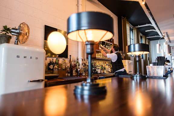 A bar with a white refrigerator and a black lamp.